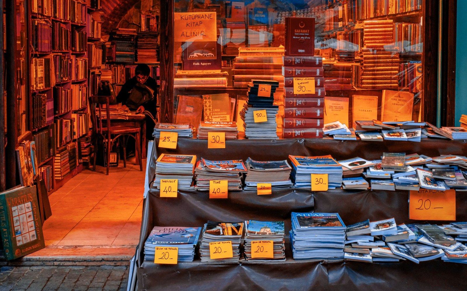 Secondhand books and magazines with price tags displayed outside a crowded bookshop